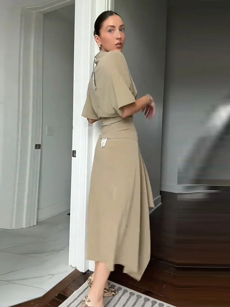 Completo da donna a due pezzi tinta unita con top a collo alto a maniche corte e gonna lunga asimmetrica drappeggiata a trapezio, outfit casual estivo da donna 2026
